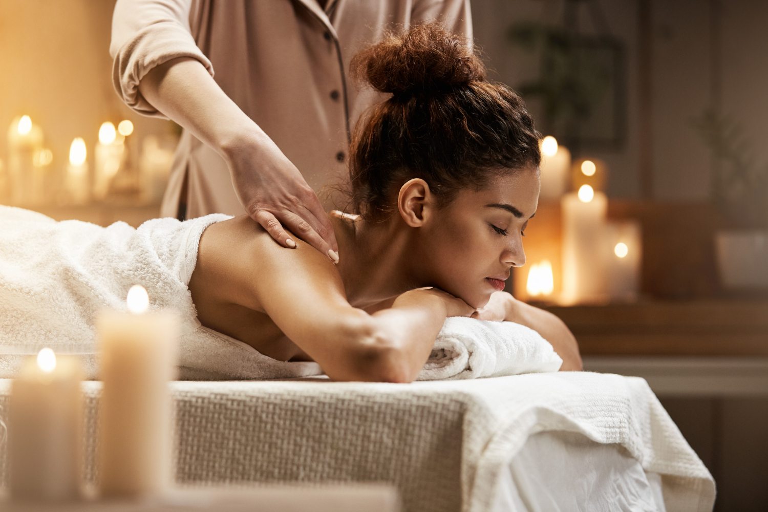 Mulher africana recebendo uma massagem, apreciando a massagem com os olhos fechados no spa resort.