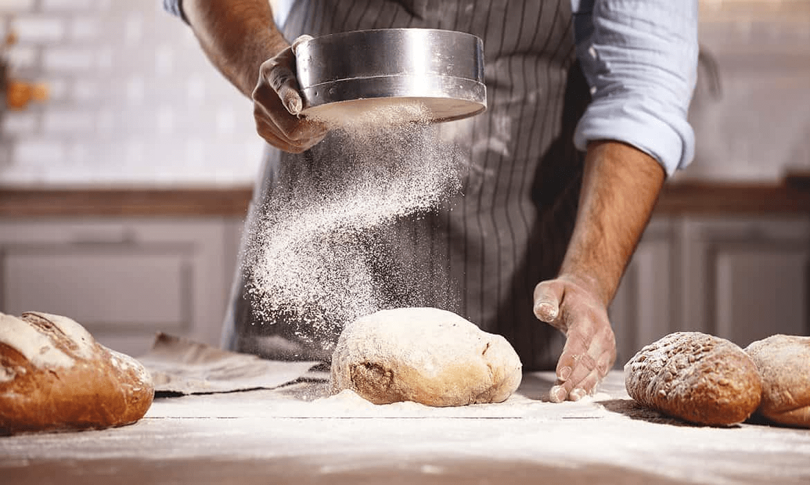 homen com a mão na massa, fazendo pães