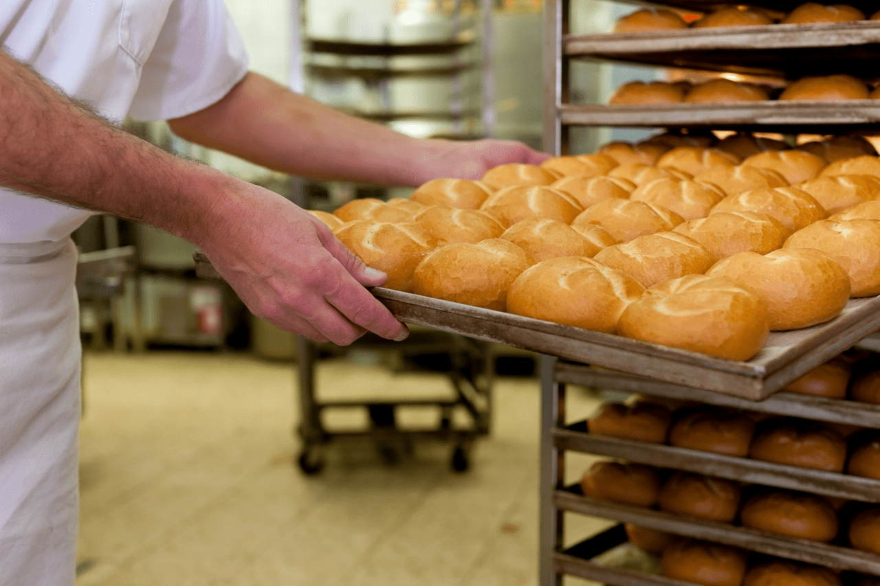Padeiro pegando uma bandeja com vários pães