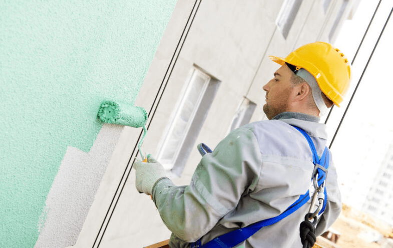 Pintor de obras, de costa pintando uma parede